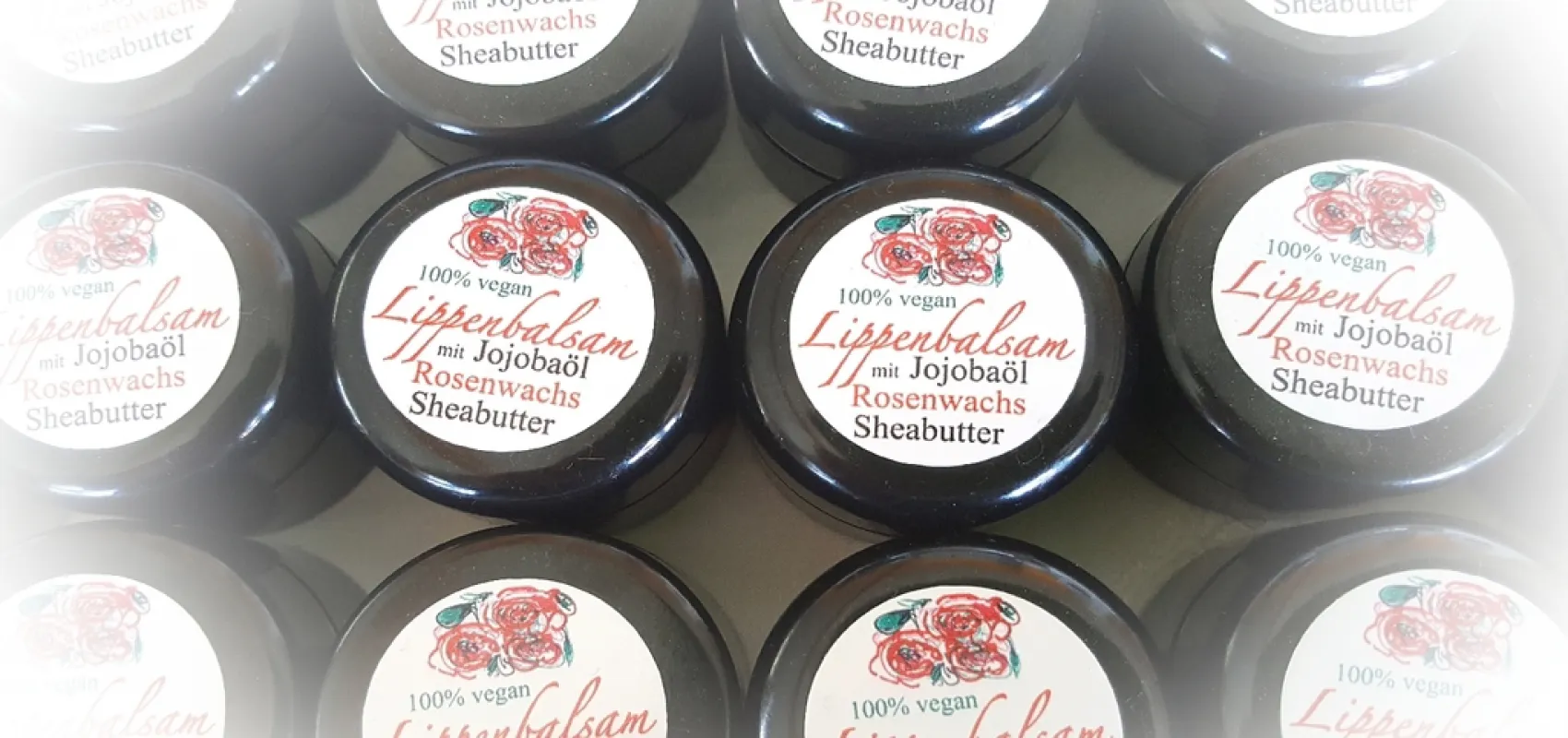 Mehrere schwarze Dosen Lippenbalsam mit Jojobaöl, Rosenwachs und Sheabutter, vegan und handgemacht von der Naturseifen Manufaktur Uckermark.